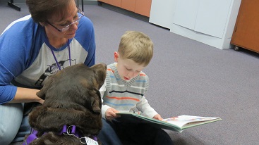 Canine and woman handler helping child learn to read
